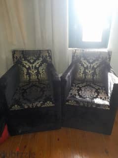 2 Black chairs with a golden design