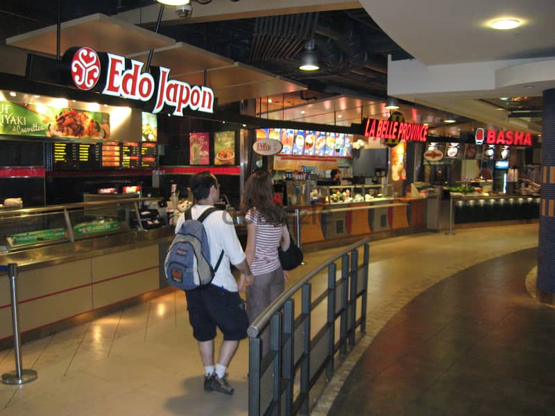 A food court restaurant facing a street and plaza view on a main axis next to Central Park and in front of the tourist towers 5
