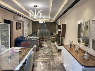 Furnished apartment for rent in Midtown compound in front of the American University in the Fifth Settlement, 200 square meters, second floor with elevator, 3 bedrooms including a master, modern furniture, and landscape view.