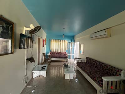 Room for rent in Lotus Village, Kilometre 91, five kilometers before Marina. Two bedrooms, fans, a bathroom, and an American kitchen. The living room is air-conditioned and covers both bedrooms. In the middle of the village, 5 minutes to the sea and five minutes to the village services. The village has all services: restaurants, cafeterias, hypermarkets, cafes, restaurants, and shops.