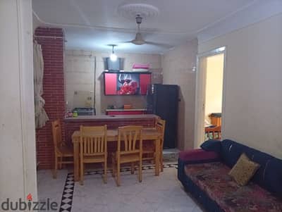 Furnished apartment for annual rent for a family, groom, student, or company. 2 bedrooms, reception area, two pieces, kitchen, bathroom, fourth floor, upper level. All amenities available: water, electricity, natural gas, and elevator. Located in Alexandria, Al-Ajami, kilometer 21, October main street, before the gate, in a very distinguished location.