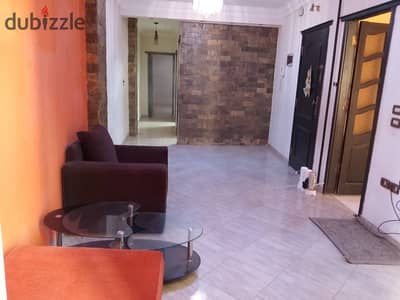 Half-furnished apartment for rent in New Maadi, 77 Street, near Swars Square and the metro station. It has an aluminum kitchen, a hood, a microwave, a heater, a sitting room, two armchairs, and a table. The apartment is on the 10th floor with an elevator and has a terrace.
