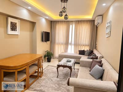 A 100-square-meter furnished apartment for rent in the Asfour El-Ganna Compound, First Settlement, located directly across from Gate 6 of Al-Rehab Cit