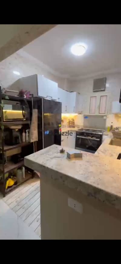 Apartment for sale with kitchen, marble, parking, and private garden, personally finished, not commercial, very special location, minutes from Mall of Egypt and downtown, a street that is lively and residential, and the building is all occupied. 3 rooms and a two-piece reception, super luxury finishing, area of 145 meters, elevated ground floor, and has a private garden and private garage.